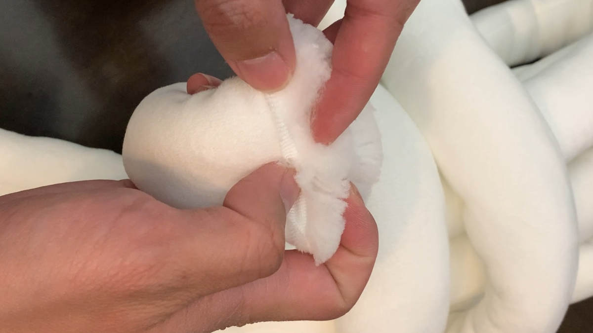 Close-up of hands opening a jumbo tube yarn to reveal its soft, high-quality inner filling, demonstrating the material’s plush texture.